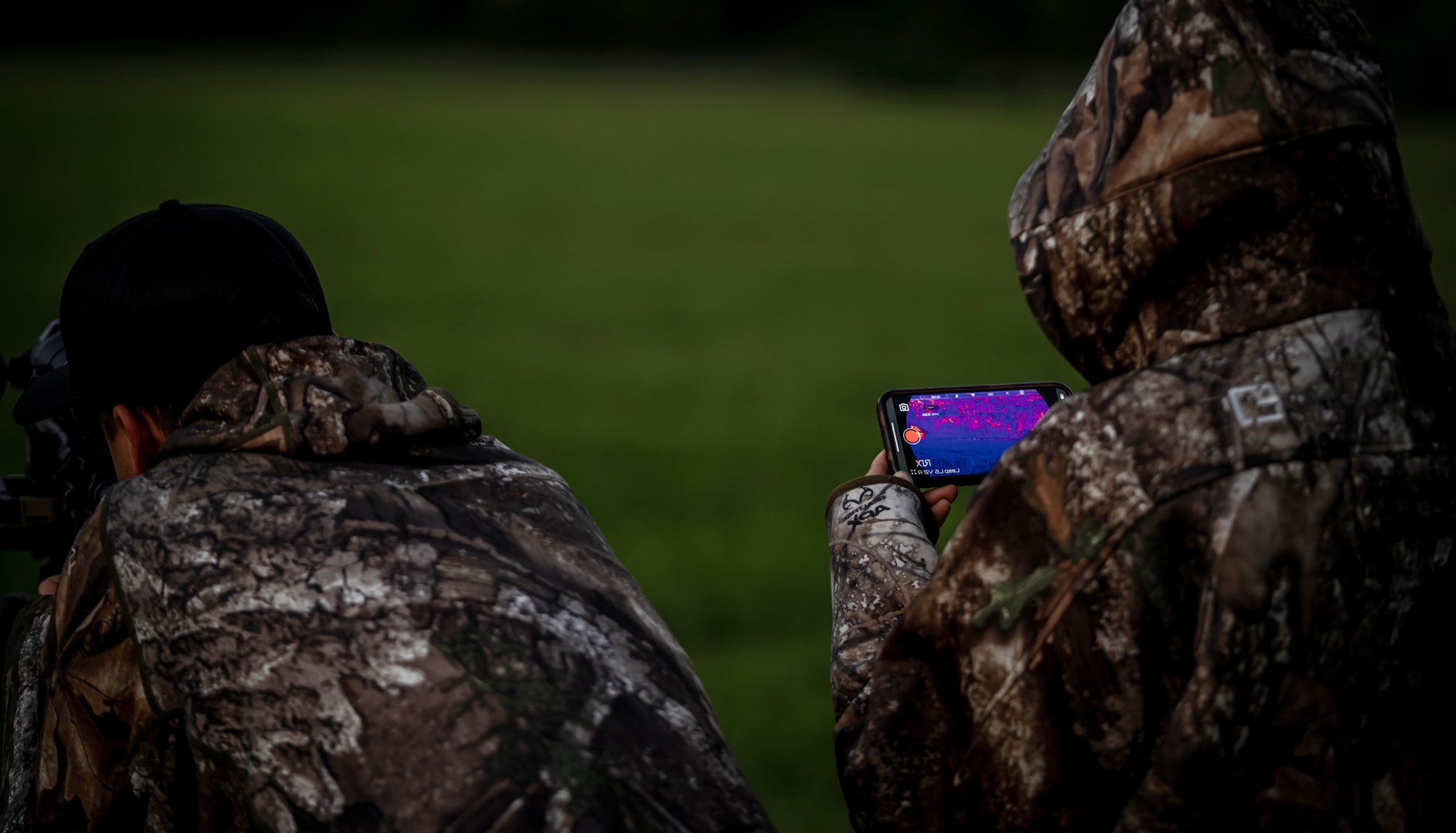 TWO HUNTERS LOOKING AT THERMAL THROUGH MOBILE PHONE